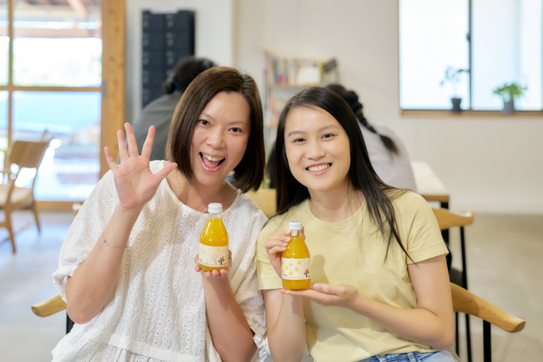 オリジナルラベルを貼ったみかんジュースを手に笑顔を見せる参加者